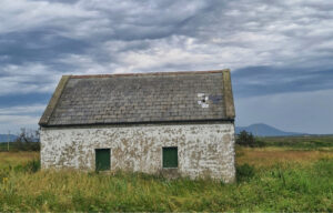 Ruine eines Cottages in Irland mit dramatisch bewölktem Himmel. Haus kaufen in Irland.