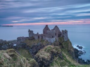 Dunluce Castle in Nordirland bei bewölktem Himmel und Sonnenuntergang. Besonders stimmungsvoll für Geschichten aus Irland und Mythen von Nadja Uebach