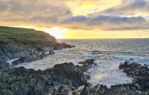 Klippen und Wellen am Wild Atlantic Way in Irland bei Sonnenungand. Zum Auswandern nach Irland gibt es viele Tipps.